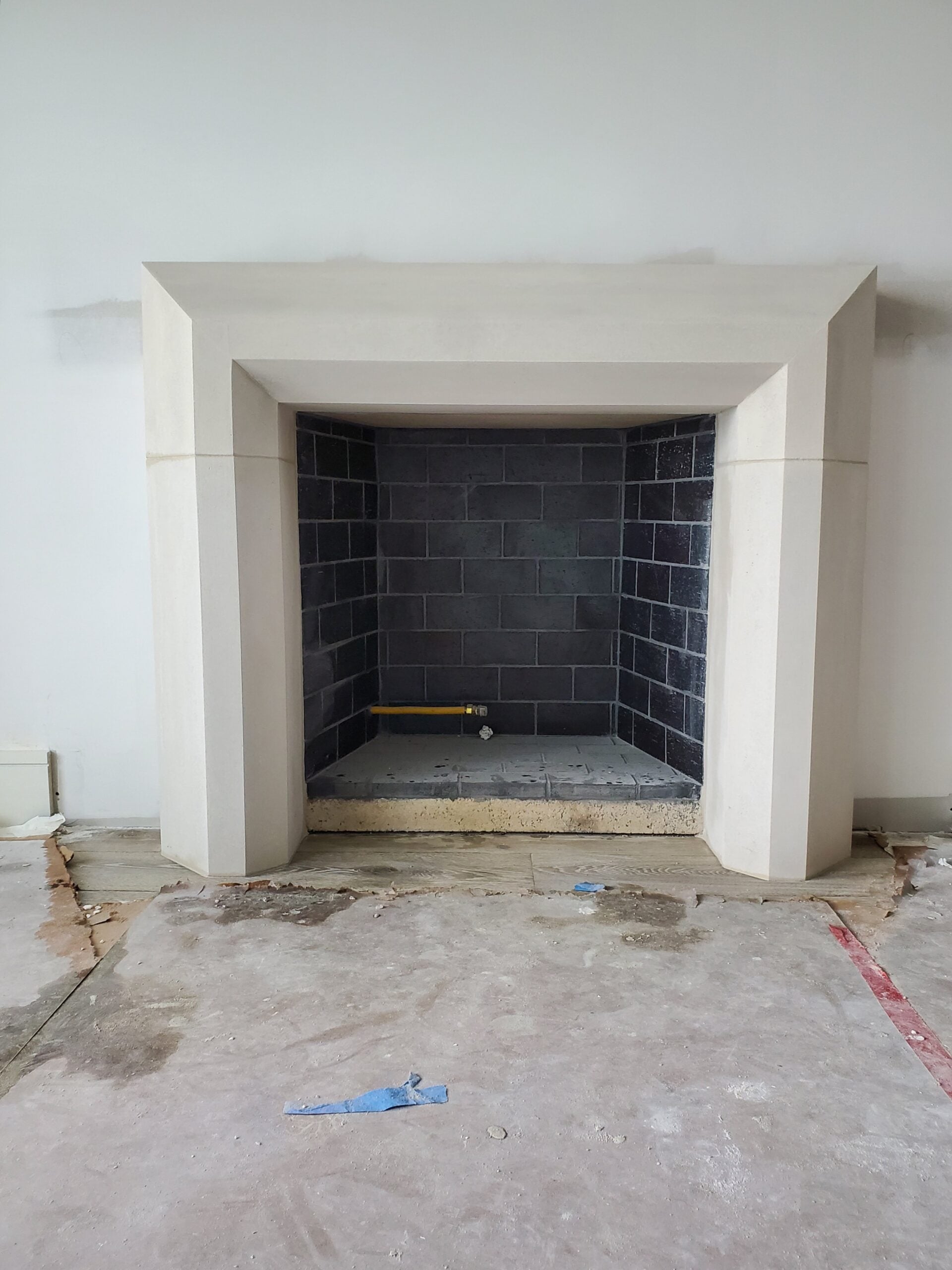 Cast-stone fireplace surround installed, dark brick interior