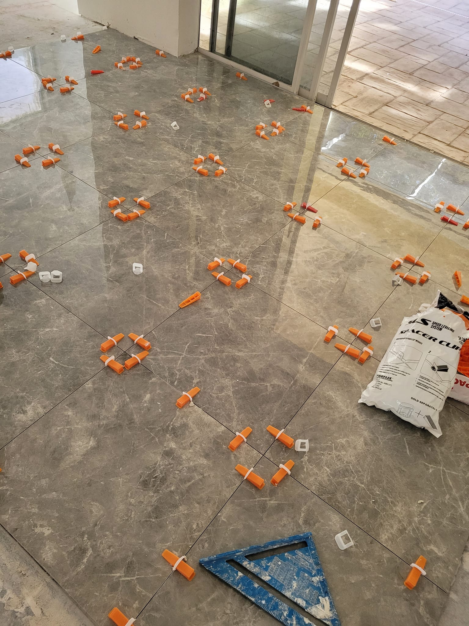 Large-format marble floor tile install in progress with spacers
