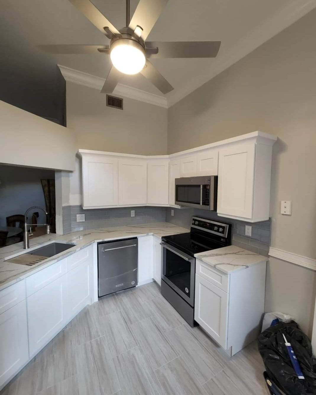 Kitchen renovation with vaulted ceiling, marble countertops, and white shaker cabinets